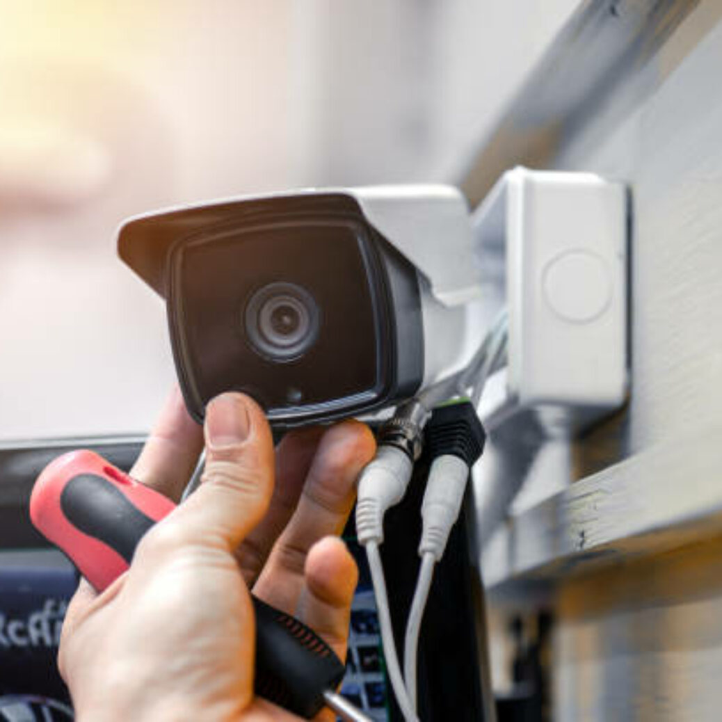 Close-up of surveillance camera installation, male hand holds cctv camera