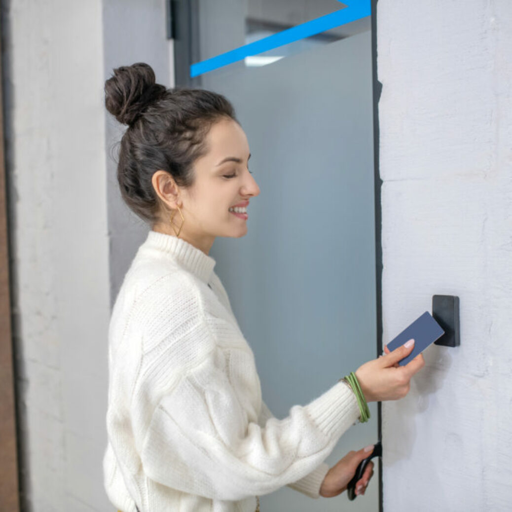 Young woman holding access card to unclock the door, smiling